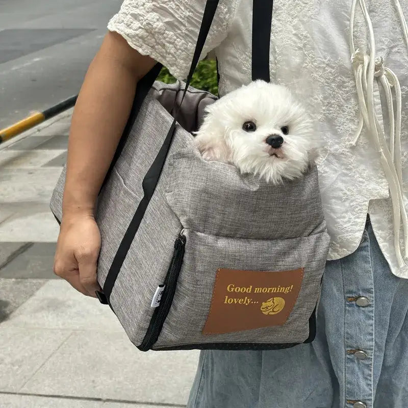 Fluffy white dog peeking out of a gray pet carrier bag.