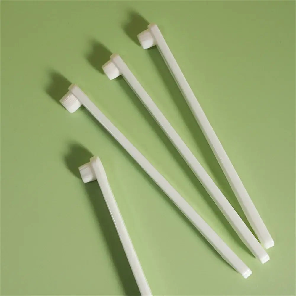 Four white plastic toothbrushes with rectangular heads.