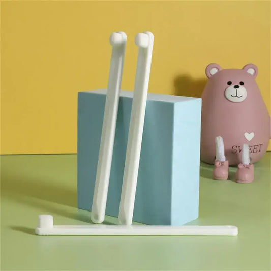 Toothbrushes leaning against a light blue cube, with a pink toy bear nearby.