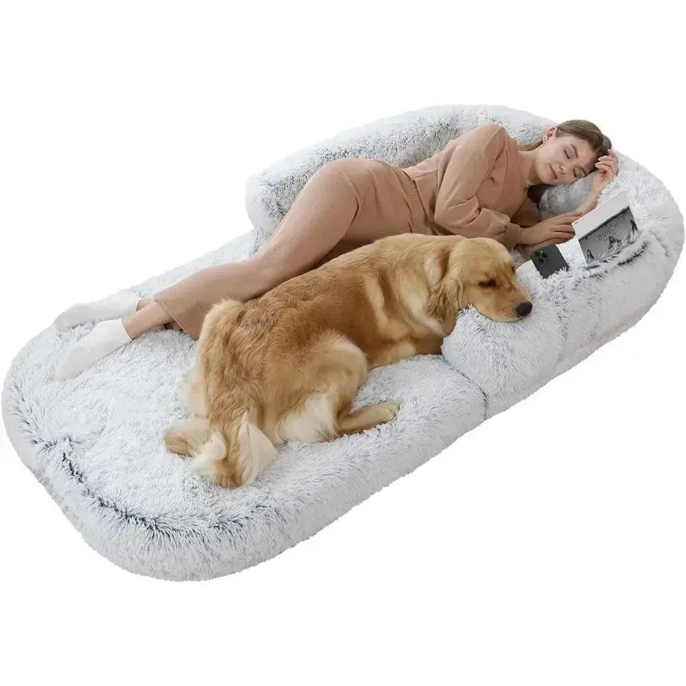 Oversized plush cushion or bed accommodating a person and a golden retriever dog.