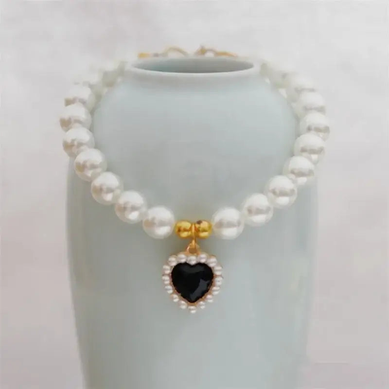 Pearl necklace with a black heart-shaped pendant surrounded by small diamonds.