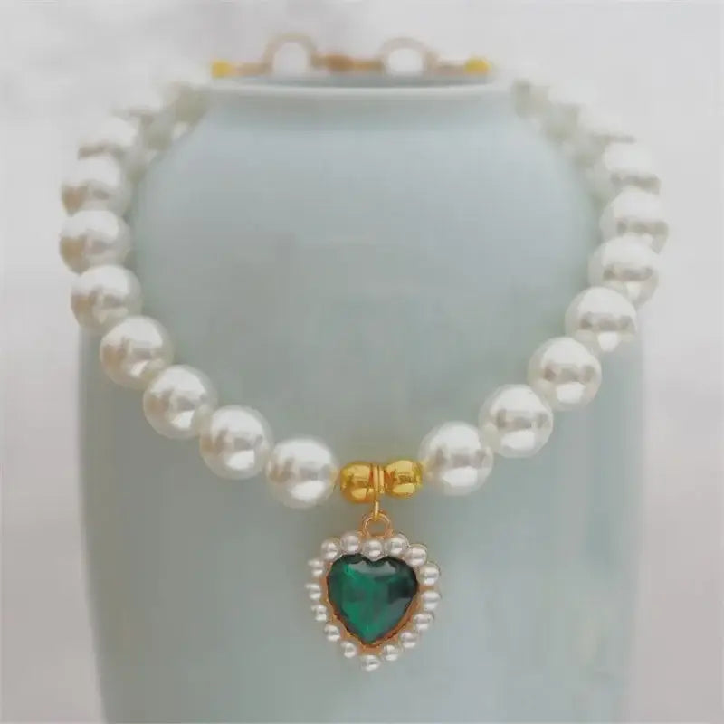 Pearl necklace with a green heart-shaped pendant surrounded by smaller pearls.