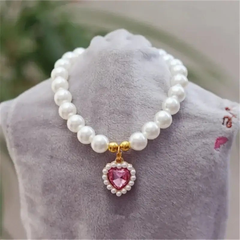 Pearl necklace with a heart-shaped pink gemstone pendant.