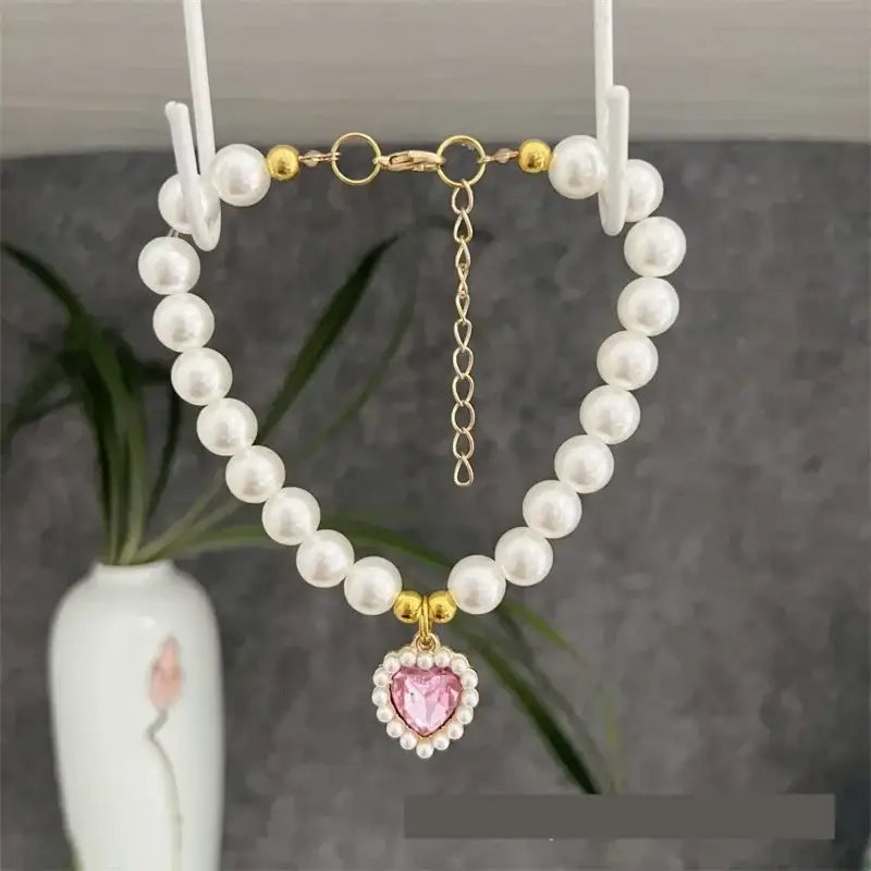 Pearl necklace with a pink heart-shaped pendant.