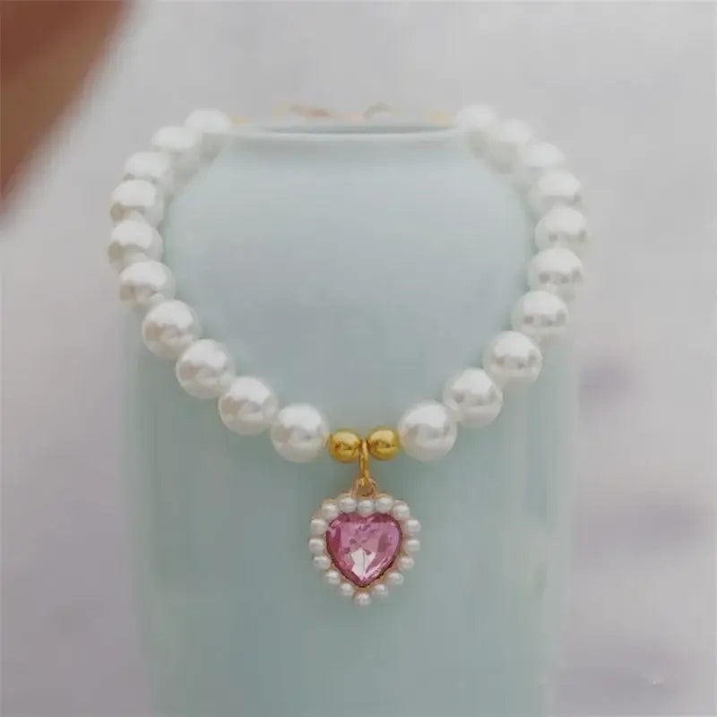 Pearl necklace with a pink heart-shaped pendant surrounded by smaller pearls.