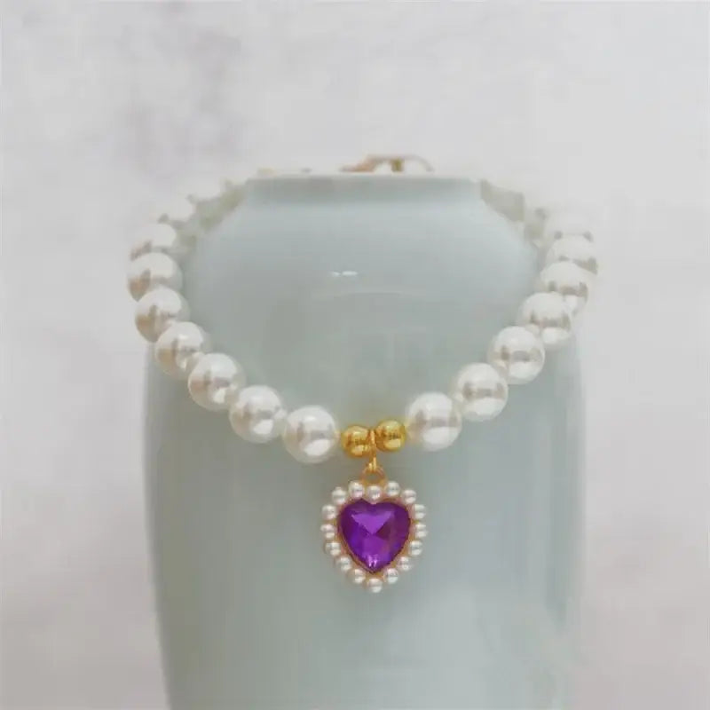 Pearl necklace with a purple heart-shaped pendant surrounded by diamonds.