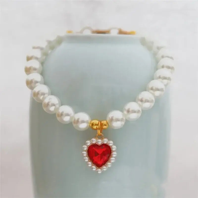 Pearl necklace with a red heart-shaped pendant.