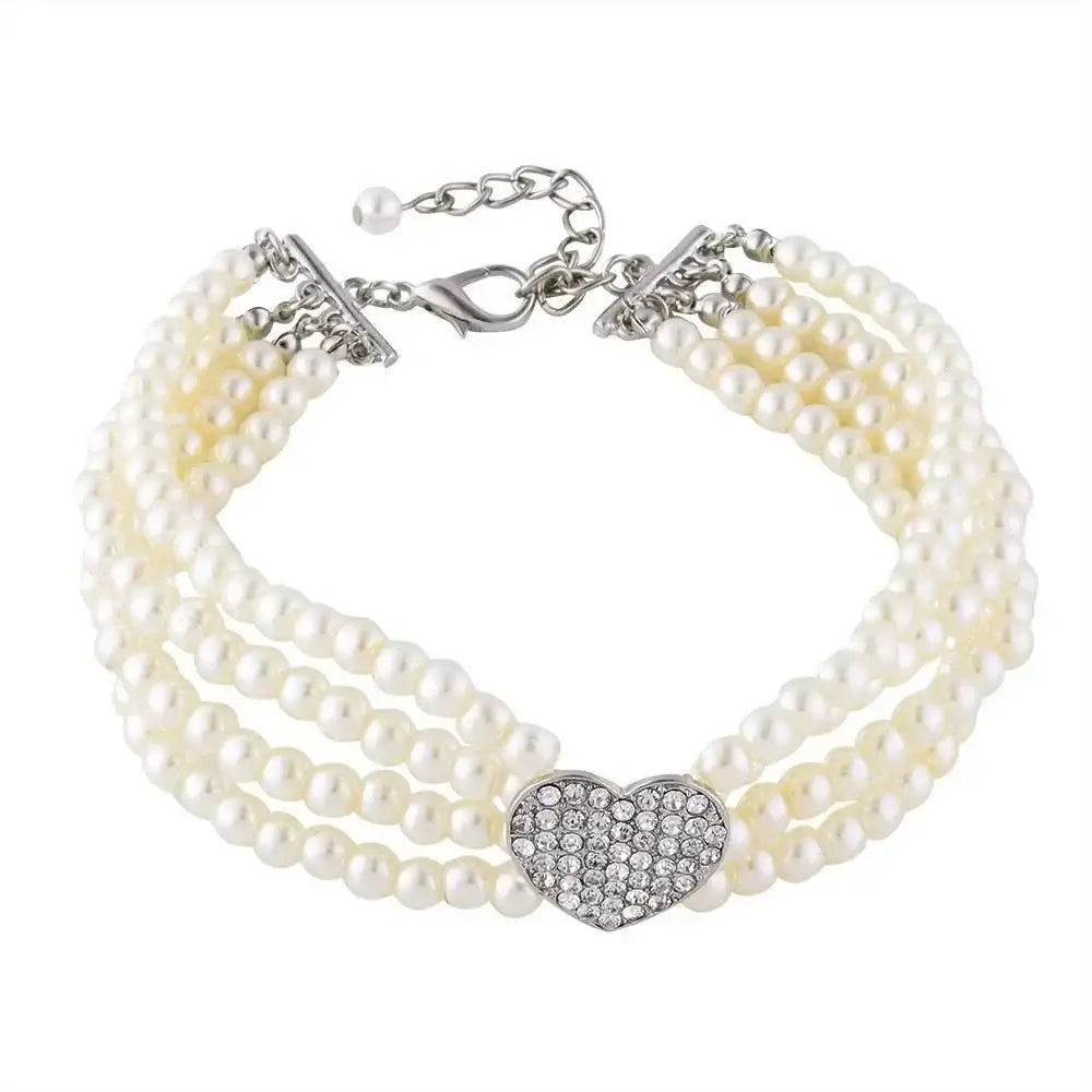 Pearl bracelet with multiple strands and a rhinestone heart centerpiece.