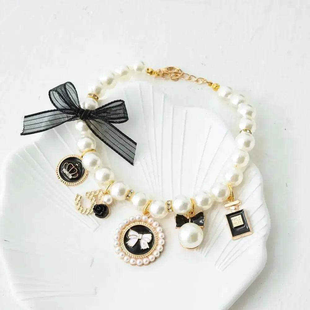 Pearl bracelet with charms and a black bow.