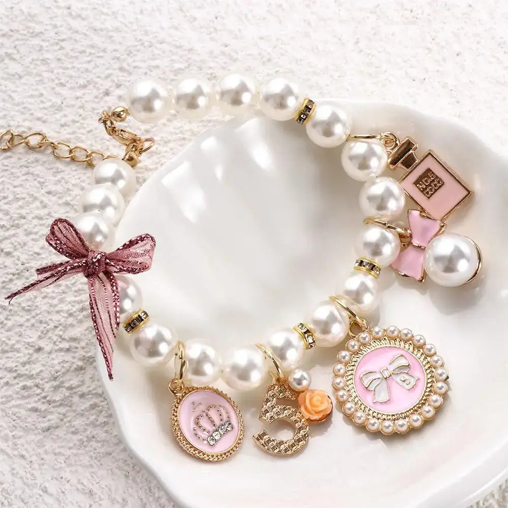 Pearl bracelet with various charms including bows, a perfume bottle, and circular pendants.