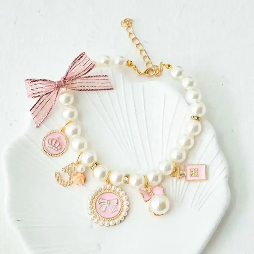 Pearl bracelet with pink bow and gold charms.