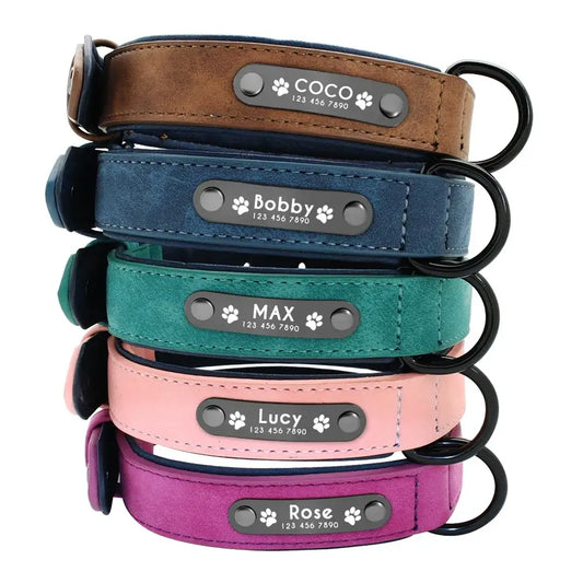 Stack of personalized leather dog collars in various colors with engraved name plates.