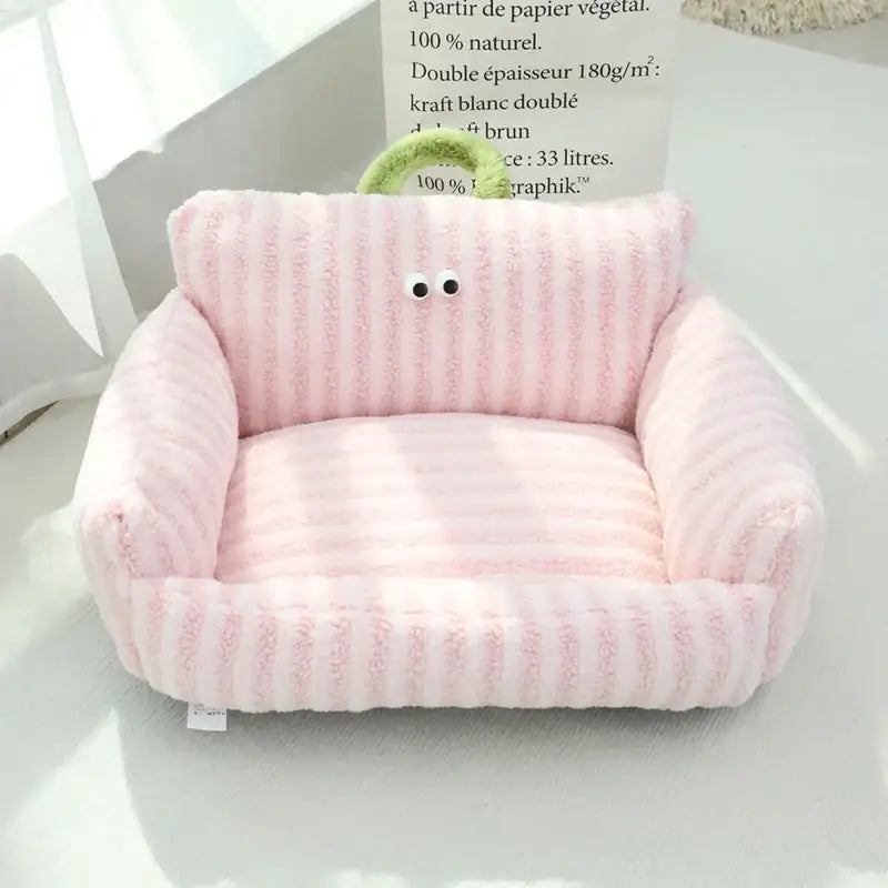 Pale pink plush pet bed with ribbed texture and simple face design.