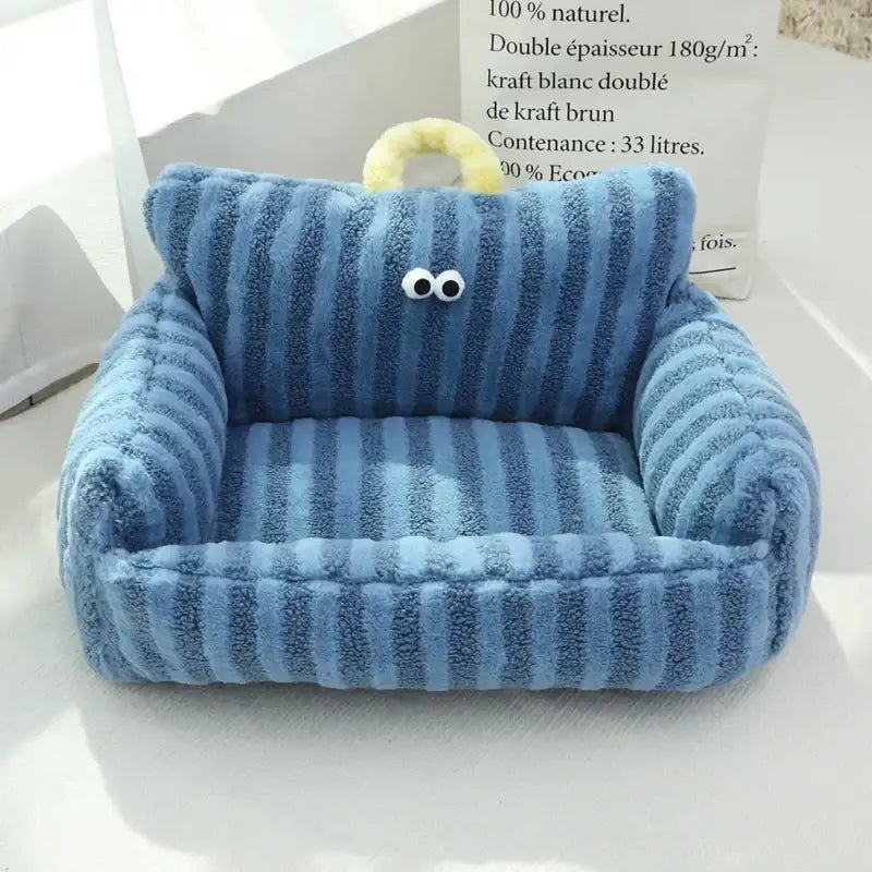 Plush blue armchair with cartoon eyes and a yellow handle on top.