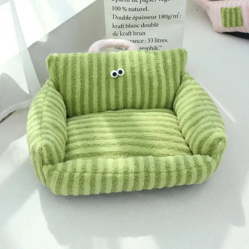 Plush green armchair with cartoon eyes attached to its back.