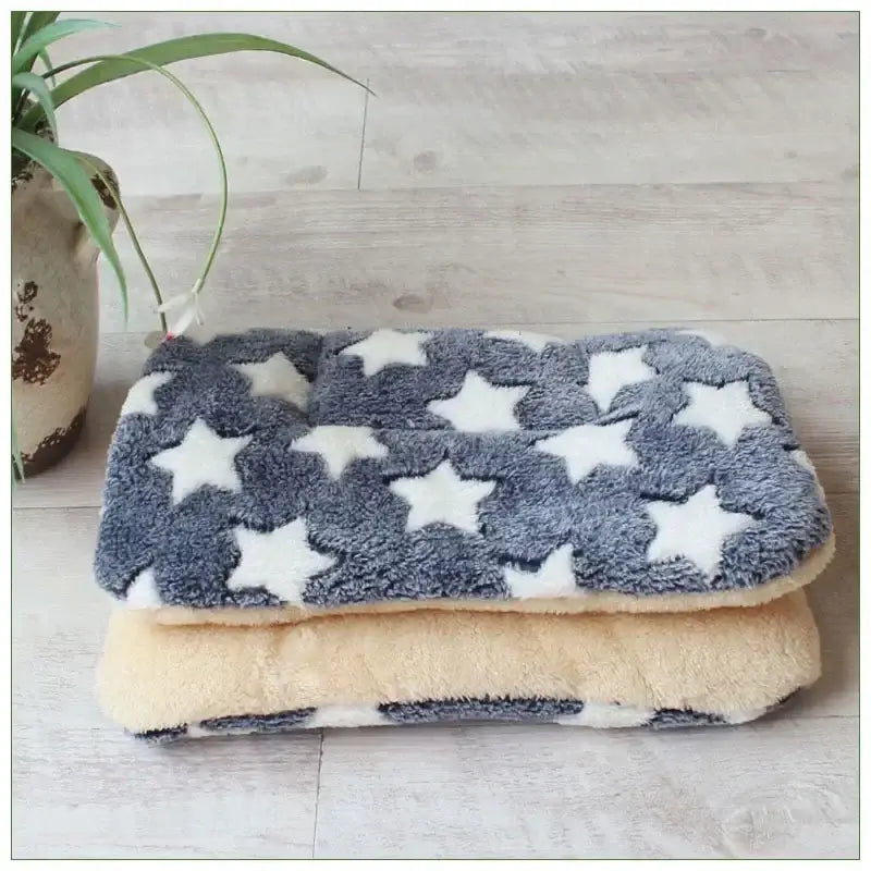 Fluffy gray pet bed with white star patterns folded on top of a beige cushion.