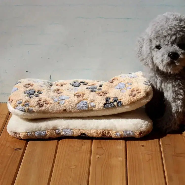 Fluffy white dog sitting next to a patterned pet bed or cushion.