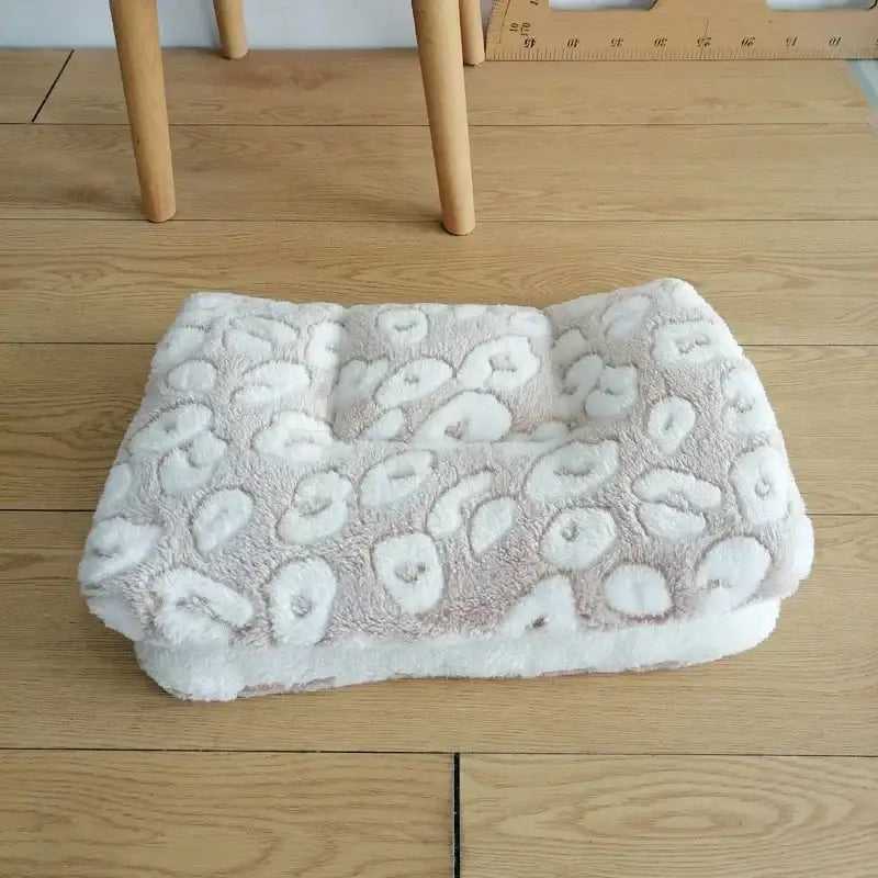 Soft, plush pet bed with a raised leopard-print pattern in light gray and white.