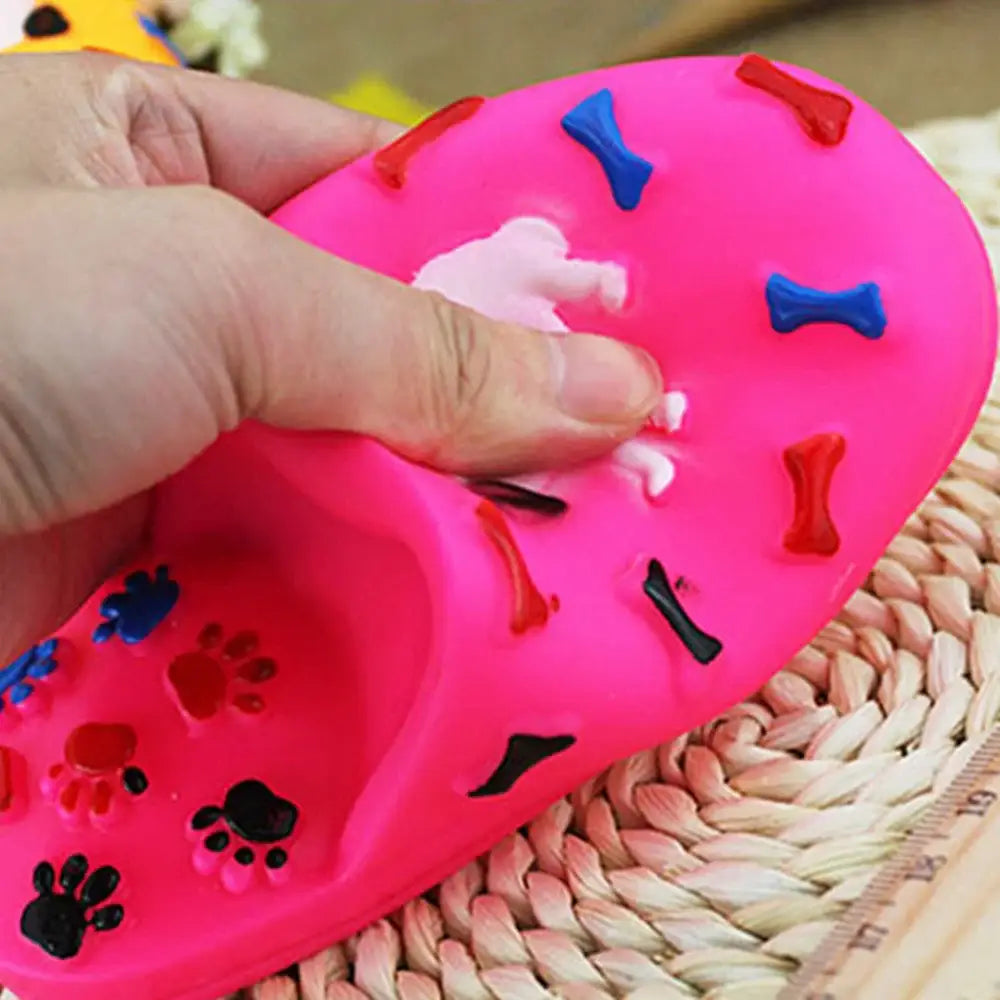 Pink rubber dog toy with colorful bone shapes and paw prints embedded in it.