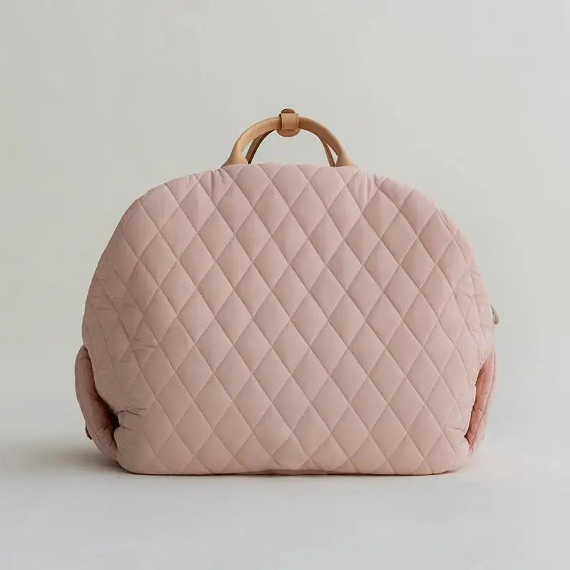 Pale pink quilted handbag with wooden handle.