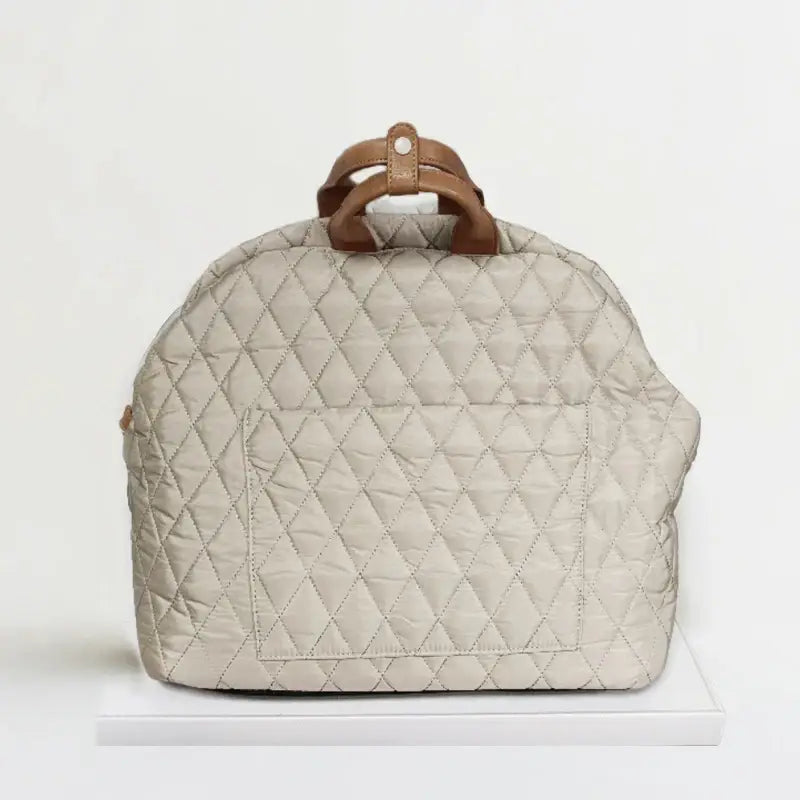 Quilted beige handbag with brown leather handles.