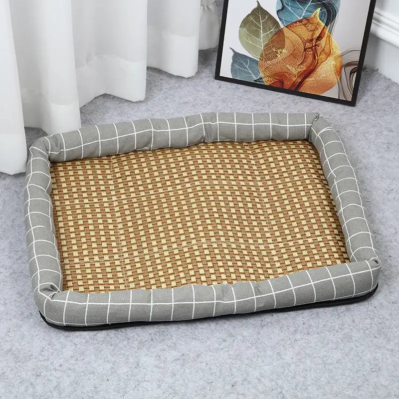 Pet bed with a gray checkered border and woven rattan mat interior.