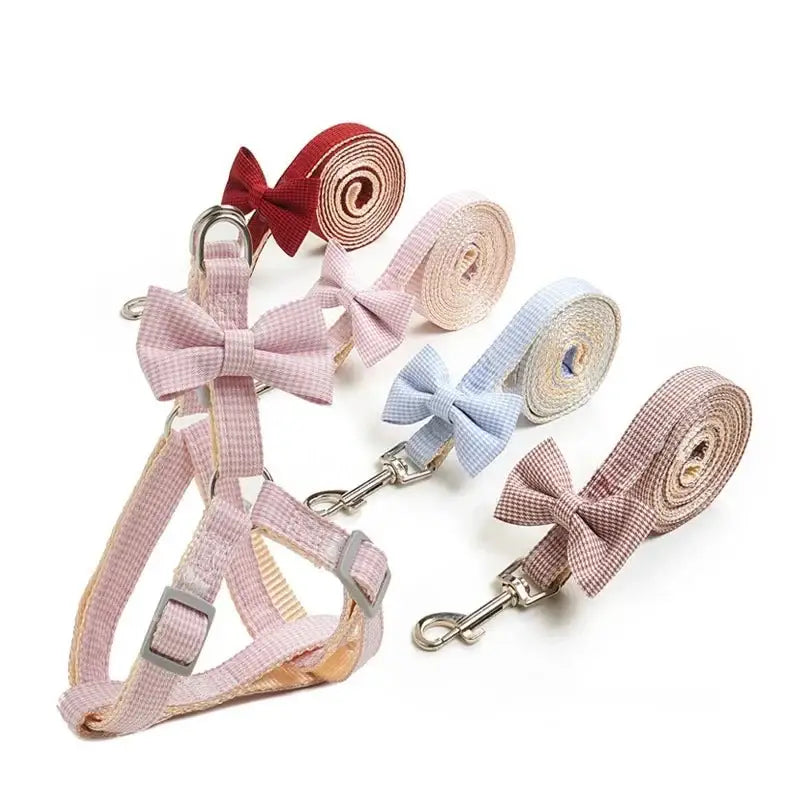 Set of pastel-colored dog harnesses and leashes with decorative bows.