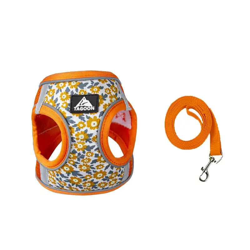 Dog harness with a floral pattern and orange trim, accompanied by a matching orange leash.