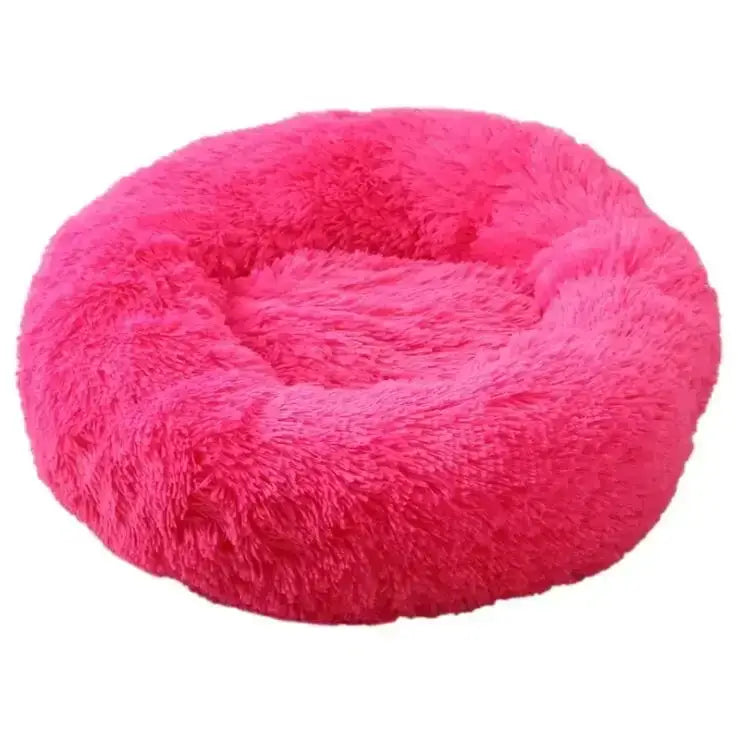 Bright pink, fluffy, circular pet bed with a raised edge and sunken center.