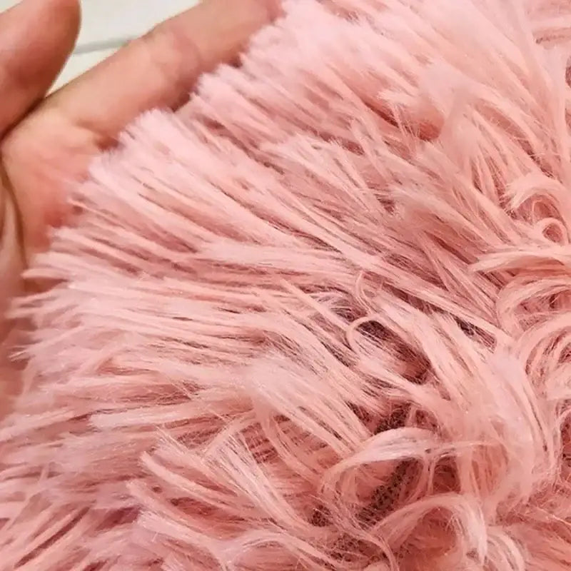 Soft, fluffy pink faux fur fabric being held by a hand.