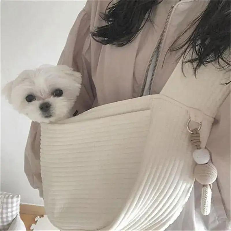 Small white dog peeking out of a light-colored handbag.