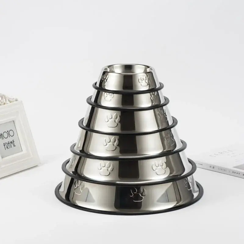 Set of stainless steel pet food bowls stacked in a pyramid shape with paw print designs.