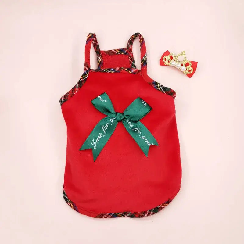 Red baby romper with a green bow and plaid trim.