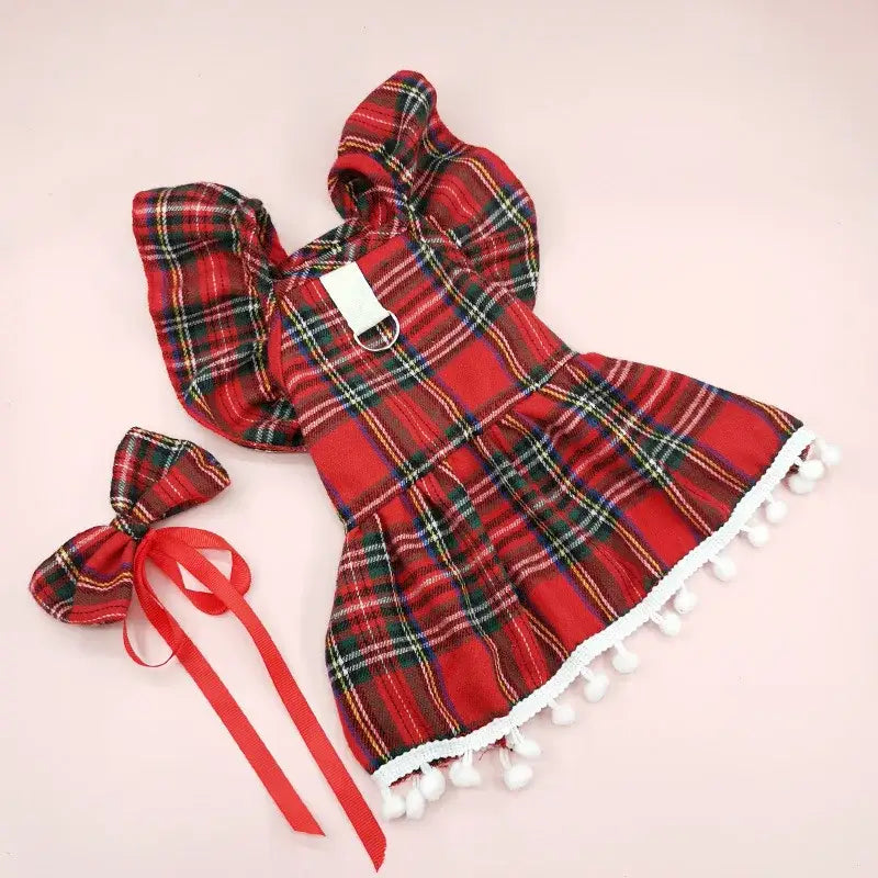 Red plaid dress with white pom-pom trim and matching hair bow.