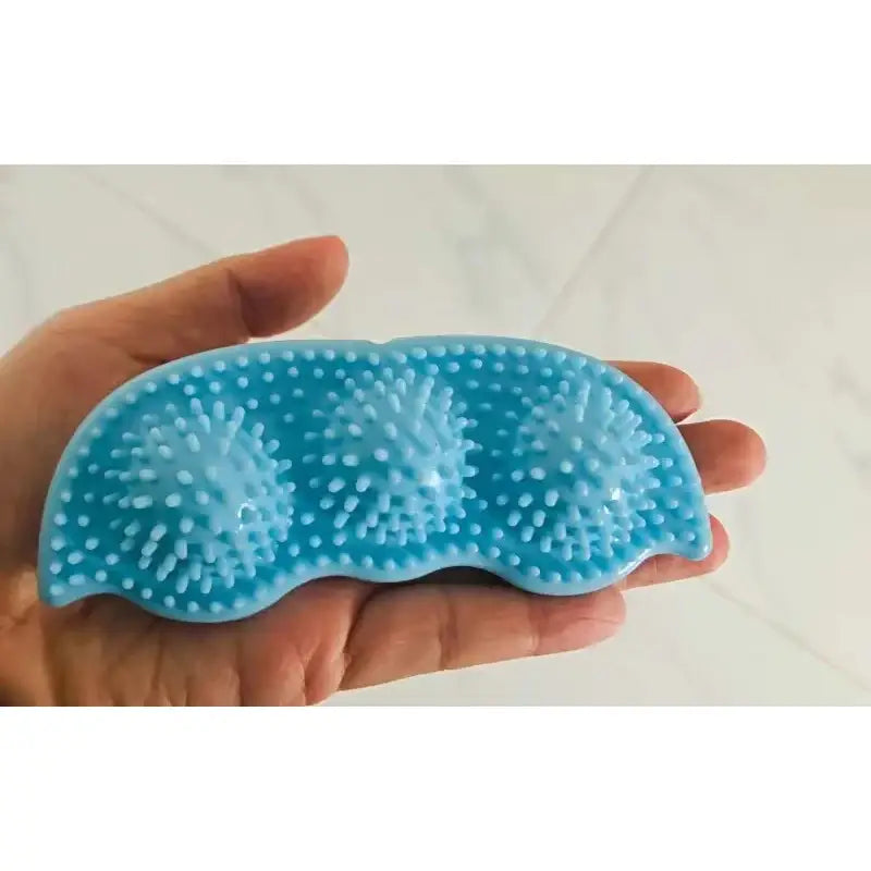 Blue silicone massage tool with raised nubs held in a hand.