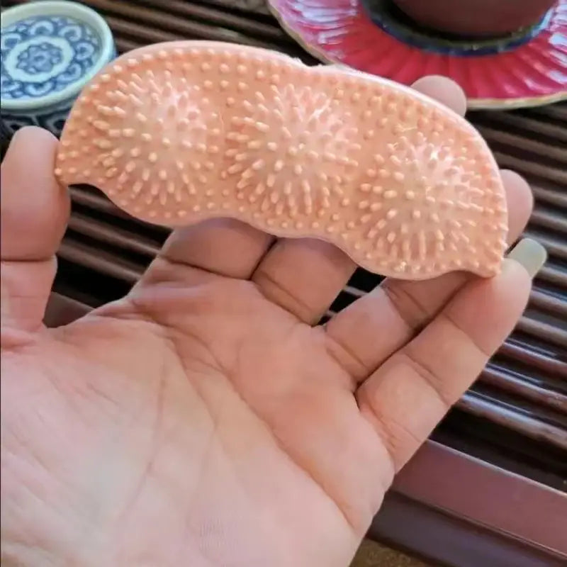 Spiky, peach-colored massage tool resting on an open palm.