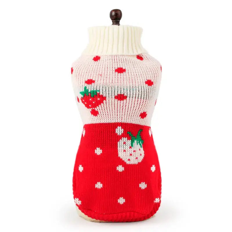 Knitted dog sweater with strawberry pattern in red and white.