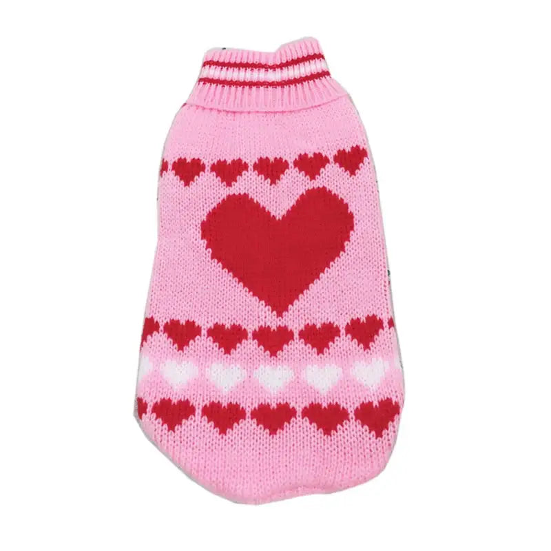 Pink knitted dog sweater with red heart patterns.