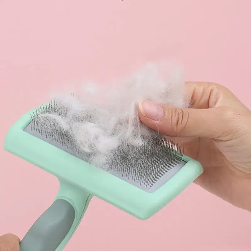 Pet grooming brush with collected fur being removed by hand.