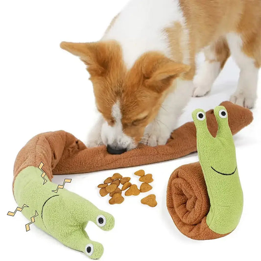 Dog sniffing a plush toy snail next to dog treats and another plush toy.