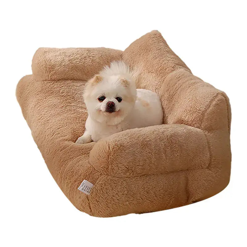 Fluffy white puppy sitting in a plush tan pet bed.