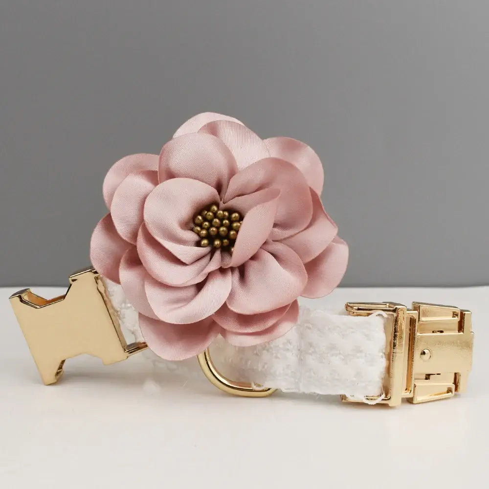 Pink fabric flower with golden center attached to a white and gold collar or strap.