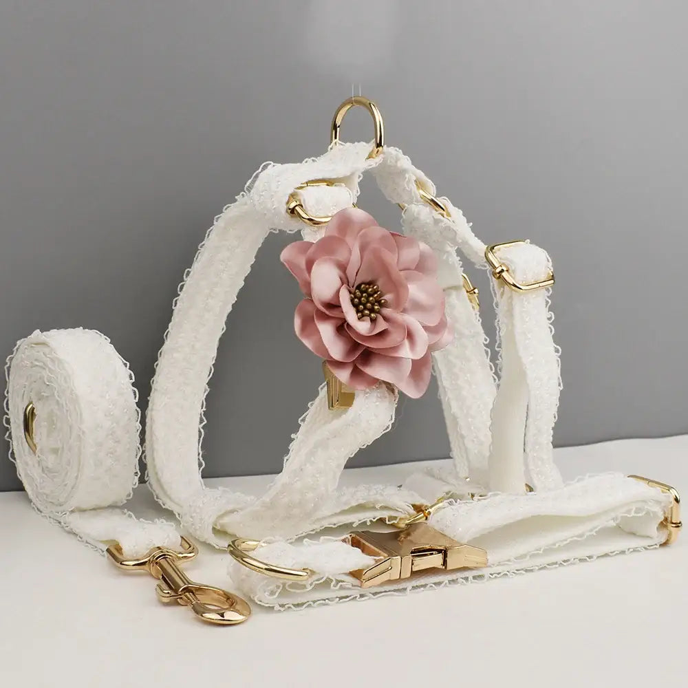 White dog harness with a pink fabric flower accent and gold hardware.