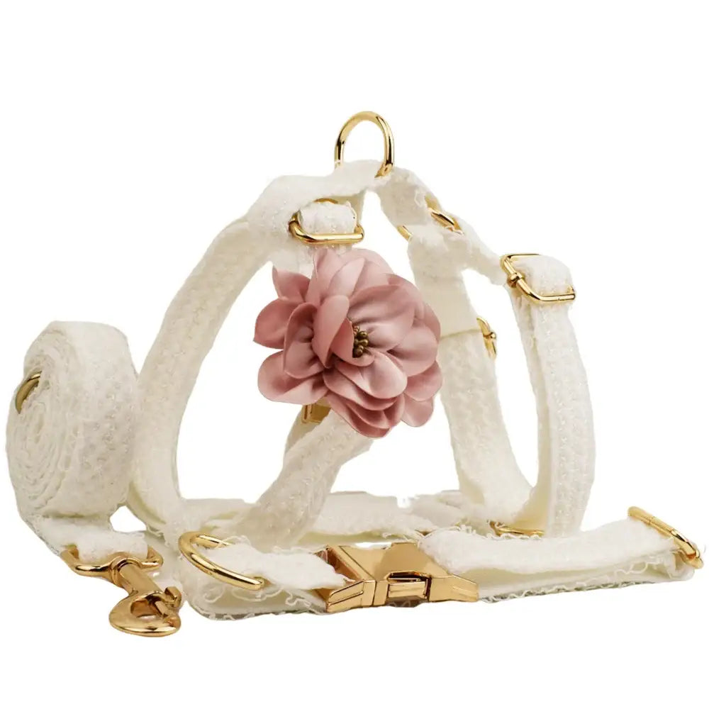 White leather dog harness with a pink fabric flower accent and gold-toned hardware.