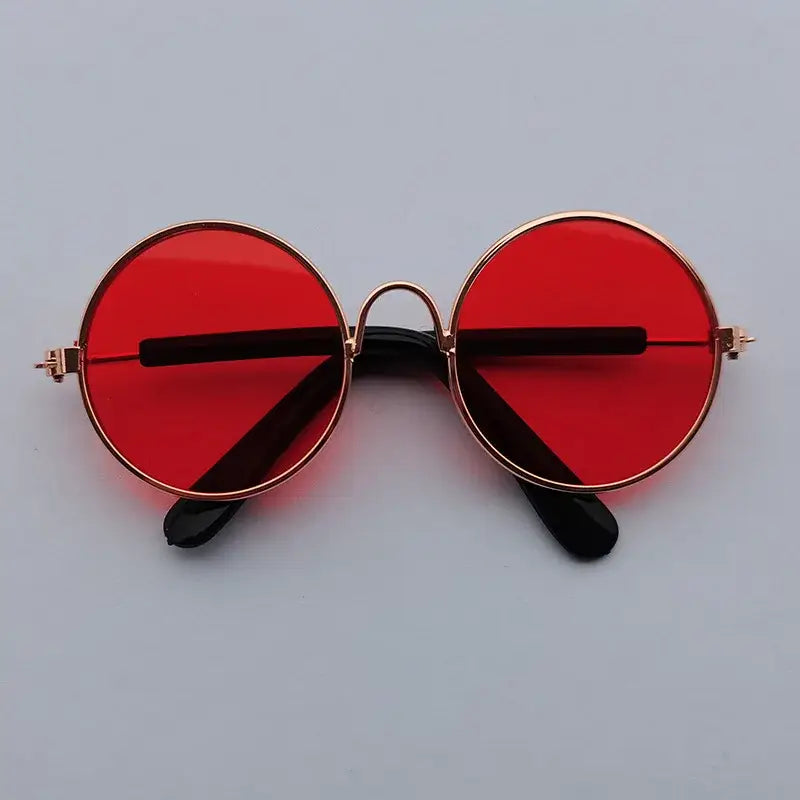 Pair of round sunglasses with red lenses and gold frames.