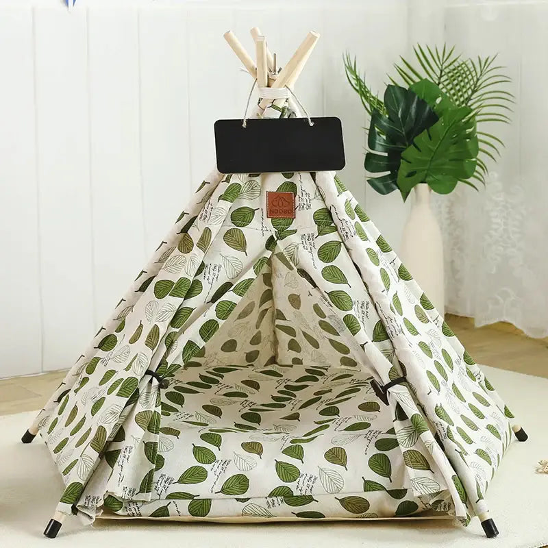 Teepee-style pet bed with a leaf pattern fabric and a small chalkboard sign.